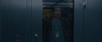 Movie still from “Arrival” (2016), directed by Denis Villeneuve – A man with a name tag is looking out of a window; Medium shot, Over the shoulder angle