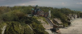 Movie still from “Artemis Fowl” (2020), directed by Kenneth Branagh – An aerial view of a building with a train tracks going down it; Extreme Wide shot, High angle