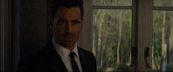 Movie still from “Artemis Fowl” (2020), directed by Kenneth Branagh – A person wearing a suit and tie; Close Up shot, Over the shoulder angle