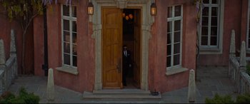 Movie still from “Artemis Fowl” (2020), directed by Kenneth Branagh – A man standing in front of an open door of a building; Extreme Wide shot, High angle