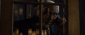 Movie still from “Artemis Fowl” (2020), directed by Kenneth Branagh – An older black man talking on a cell phone through a window; Close Up shot, High angle