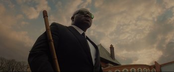 Movie still from “Artemis Fowl” (2020), directed by Kenneth Branagh – A man in a suit and sunglasses holding a cane; Medium shot, Low angle