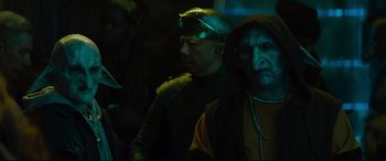 Movie still from “Artemis Fowl” (2020), directed by Kenneth Branagh – A group of people standing in a dark room; Close Up shot, Over the shoulder angle