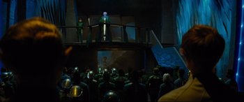 Movie still from “Artemis Fowl” (2020), directed by Kenneth Branagh – A group of people standing in front of an audience; Wide shot, Over the shoulder angle