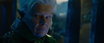 Movie still from “Artemis Fowl” (2020), directed by Kenneth Branagh – An old woman with white hair and a green shirt; Close Up shot, Over the shoulder angle