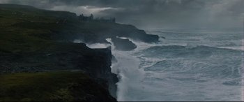 Movie still from “Artemis Fowl” (2020), directed by Kenneth Branagh – A view of the ocean from a cliff with waves crashing on it; Extreme Wide shot, Low angle