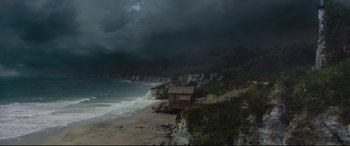 Movie still from “Artemis Fowl” (2020), directed by Kenneth Branagh – A house sitting on the side of a cliff by the ocean; Extreme Wide shot, High angle