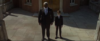 Movie still from “Artemis Fowl” (2020), directed by Kenneth Branagh – A man and a boy dressed up in suits and ties; Wide shot, Low angle