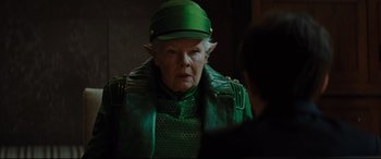 Movie still from “Artemis Fowl” (2020), directed by Kenneth Branagh – An older woman wearing a green hat and a green leather jacket; Close Up shot, Over the shoulder angle