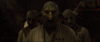 Movie still from “Artemis Fowl” (2020), directed by Kenneth Branagh – A group of people that are standing in the dark; Close Up shot, Low angle