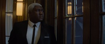 Movie still from “Artemis Fowl” (2020), directed by Kenneth Branagh – A man in a suit and tie looking out of a window; Medium shot, Low angle