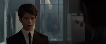 Movie still from “Artemis Fowl” (2020), directed by Kenneth Branagh – A man in a suit and tie standing in front of a window; Close Up shot, Over the shoulder angle