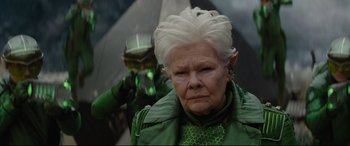 Movie still from “Artemis Fowl” (2020), directed by Kenneth Branagh – An older woman in a green outfit with a green mask; Close Up shot, Low angle