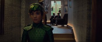Movie still from “Artemis Fowl” (2020), directed by Kenneth Branagh – A young boy dressed in a green costume in a living room; Medium shot, Over the shoulder angle