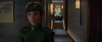 Movie still from “Artemis Fowl” (2020), directed by Kenneth Branagh – A young boy dressed in a green outfit; Medium shot, Over the shoulder angle