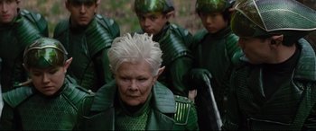 Movie still from “Artemis Fowl” (2020), directed by Kenneth Branagh – An older woman in a green outfit with a bunch of young men; Close Up shot, Over the shoulder angle