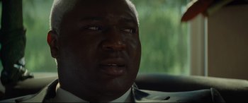 Movie still from “Artemis Fowl” (2020), directed by Kenneth Branagh – A person in a suit and tie; Close Up shot, Over the shoulder angle