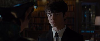 Movie still from “Artemis Fowl” (2020), directed by Kenneth Branagh – A boy in a suit and tie in a library; Close Up shot, Over the shoulder angle