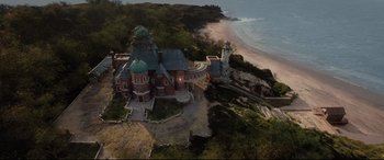 Movie still from “Artemis Fowl” (2020), directed by Kenneth Branagh – An aerial view of an old building on the beach; Extreme Wide shot, High angle