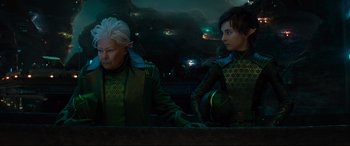 Movie still from “Artemis Fowl” (2020), directed by Kenneth Branagh – Two women in green outfits sitting next to each other; Medium shot, Over the shoulder angle