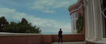 Movie still from “Artemis Fowl” (2020), directed by Kenneth Branagh – A man in a suit standing in front of the ocean; Extreme Wide shot, Low angle