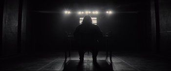 Movie still from “Artemis Fowl” (2020), directed by Kenneth Branagh – A person sitting in a dark room with lights on; Wide shot, Low angle