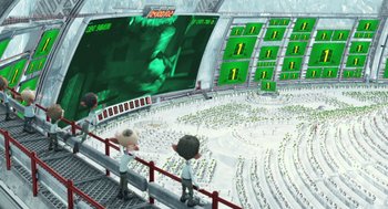 Movie still from “Arthur Christmas” (2011), directed by Barry Cook – Two people standing in front of a large screen in an arena; Extreme Wide shot, High angle