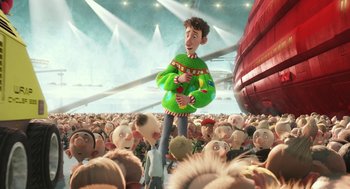 Movie still from “Arthur Christmas” (2011), directed by Barry Cook – A crowd of people are gathered around a man in a green sweater; Medium shot, Low angle