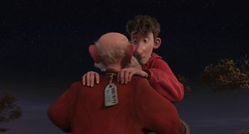 Movie still from “Arthur Christmas” (2011), directed by Barry Cook – A man is hugging another man with a price tag hanging from the back of his head; Medium shot, Over the shoulder angle