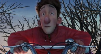 Movie still from “Arthur Christmas” (2011), directed by Barry Cook – A man riding a bike with trees in the background; Close Up shot, High angle