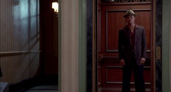 Movie still from “As Good as It Gets” (1997), directed by James L. Brooks – A man in a hat standing in front of an open door; Wide shot, Low angle