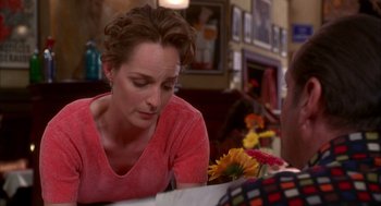 Movie still from “As Good as It Gets” (1997), directed by James L. Brooks – A woman sitting at a table looking down at flowers; Close Up shot, Over the shoulder angle