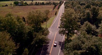 Movie still from “As Good as It Gets” (1997), directed by James L. Brooks – Two cars driving down a road surrounded by trees; Extreme Wide shot, High angle