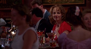 Movie still from “As Good as It Gets” (1997), directed by James L. Brooks – A woman sitting at a table with a glass of wine; Medium shot, Over the shoulder angle