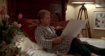 Movie still from “As Good as It Gets” (1997), directed by James L. Brooks – A man and a dog sitting on a bed reading a paper; Medium shot, Low angle