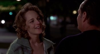 Movie still from “As Good as It Gets” (1997), directed by James L. Brooks – A woman smiling at the camera while sitting on a bench; Close Up shot, Over the shoulder angle