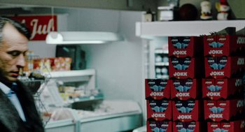 Movie still from “As It Is in Heaven” (2004), directed by Kay Pollak – A stack of jokkbox boxes in a grocery store; Medium shot, Over the shoulder angle
