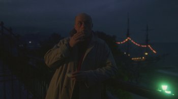 A man in a trench coat is holding a nintendo wii controller in his hand
