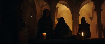 Movie still from “Assassin's Creed” (2016), directed by Justin Kurzel – Two people are sitting in a room with a candle; Wide shot, Low angle