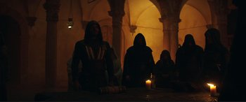 Movie still from “Assassin's Creed” (2016), directed by Justin Kurzel – A group of people standing around a candle lit room; Wide shot, Low angle