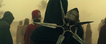 Movie still from “Assassin's Creed” (2016), directed by Justin Kurzel – A metal sculpture with a person in the background; Medium shot, Over the shoulder angle