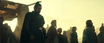 Movie still from “Assassin's Creed” (2016), directed by Justin Kurzel – A group of people standing next to each other in a field; Medium shot, Low angle