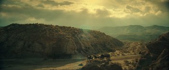 Movie still from “Assassin's Creed” (2016), directed by Justin Kurzel – A horse drawn carriage traveling down a dirt road near a mountain; Extreme Wide shot, Low angle