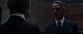 Movie still from “Assassin's Creed” (2016), directed by Justin Kurzel – A man in a suit and tie standing next to another man in a suit and tie; Close Up shot, Over the shoulder angle
