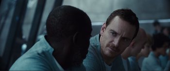 Movie still from “Assassin's Creed” (2016), directed by Justin Kurzel – Two men are sitting in a car and one of them is looking at the camera; Close Up shot, Over the shoulder angle