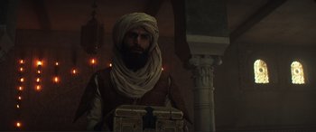Movie still from “Assassin's Creed” (2016), directed by Justin Kurzel – A man with a beard wearing a turban and holding a box; Medium shot, Low angle