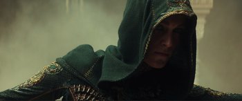 Movie still from “Assassin's Creed” (2016), directed by Justin Kurzel – A person with a green hood is looking at the camera; Close Up shot, Low angle