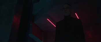 Movie still from “Assassin's Creed” (2016), directed by Justin Kurzel – A man standing in a dark room with a red light behind him; Medium shot, Low angle