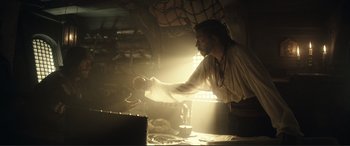 Movie still from “Assassin's Creed” (2016), directed by Justin Kurzel – A man in white shirt holding a ball in a room; Medium shot, Low angle