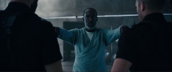 Movie still from “Assassin's Creed” (2016), directed by Justin Kurzel – A man standing in a room with his arms outstreched; Medium shot, Over the shoulder angle